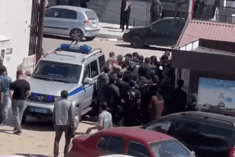 People reportedly gather around an official vehicle in Khasavyurt, Daghestan. Screengrab from video on social media.