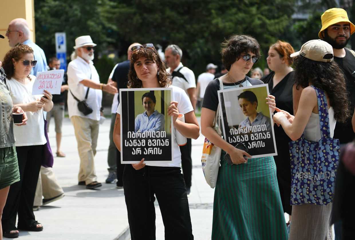 Activists at Batumi City Court holding photos of Mzia Amaghlobeli, featuring a quote from one of her statements from prison: ‘Fight before it’s too late’. Photo: Mariam Nikuradze/OC Media