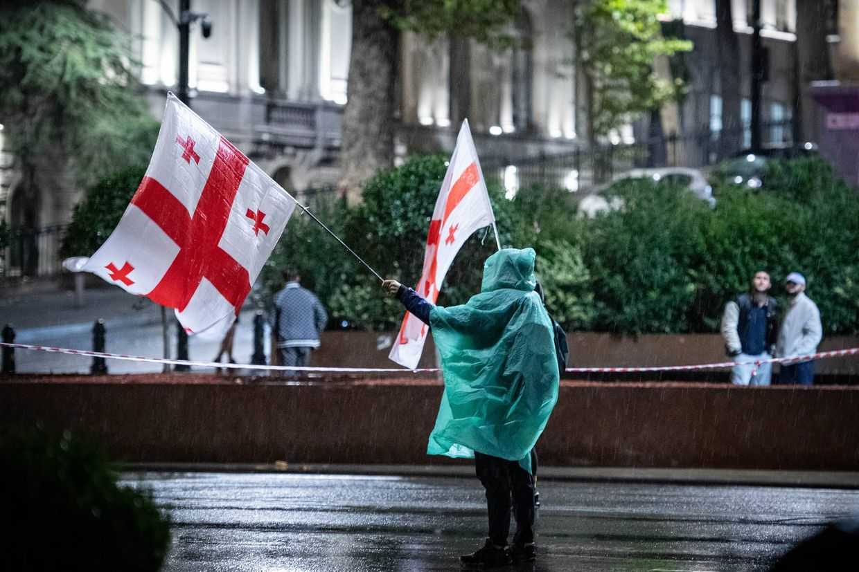 A demonstrator holding Georgian flags protests in front of parliament. Photo: Mariam Nikuradze/OC Media.