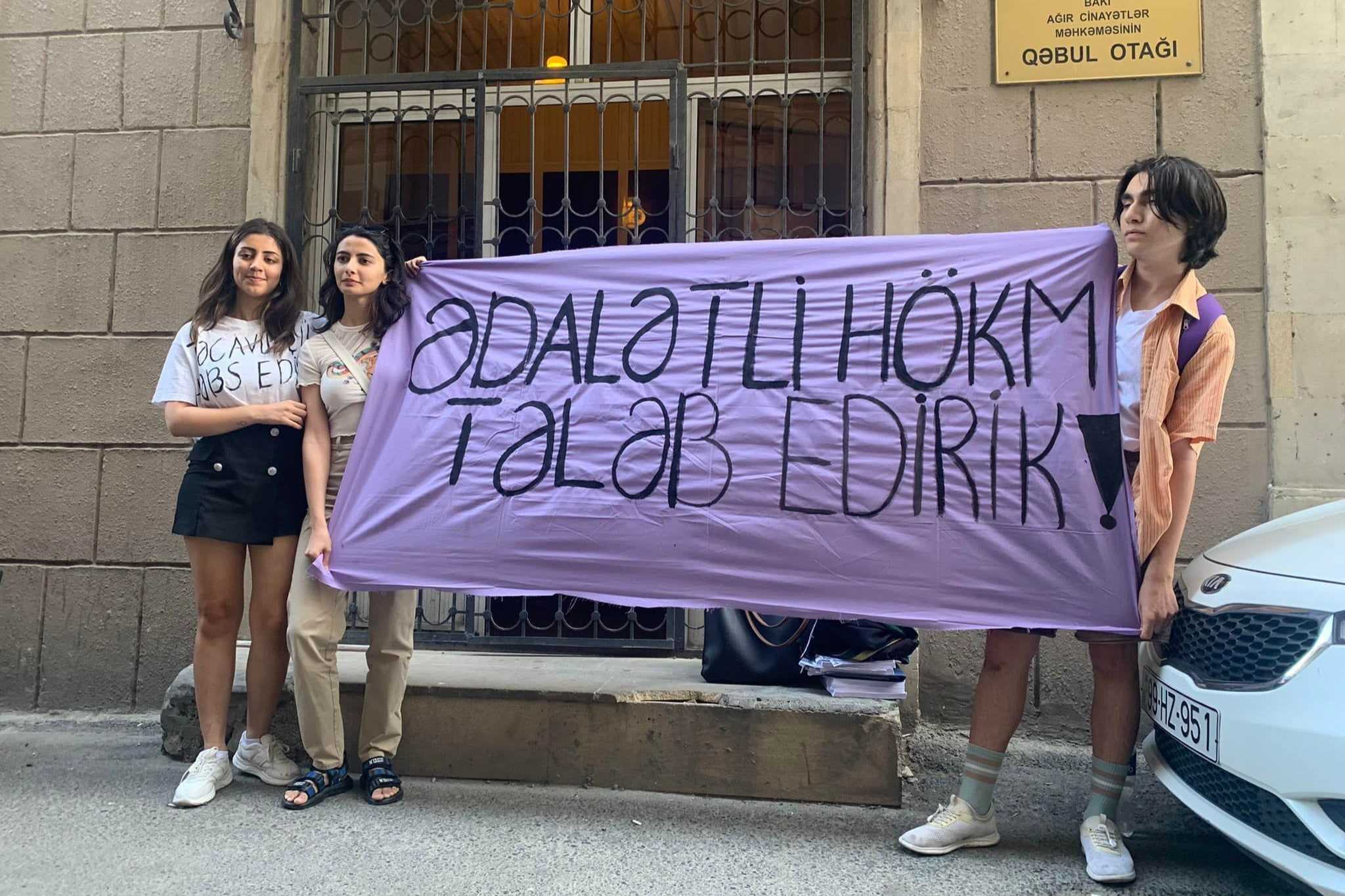 Sanay Yaghmur (left) with two other activists protesting outside the Baku Court of Grave Crimes on 29 June. The banner reads: ‘we demand justice’.