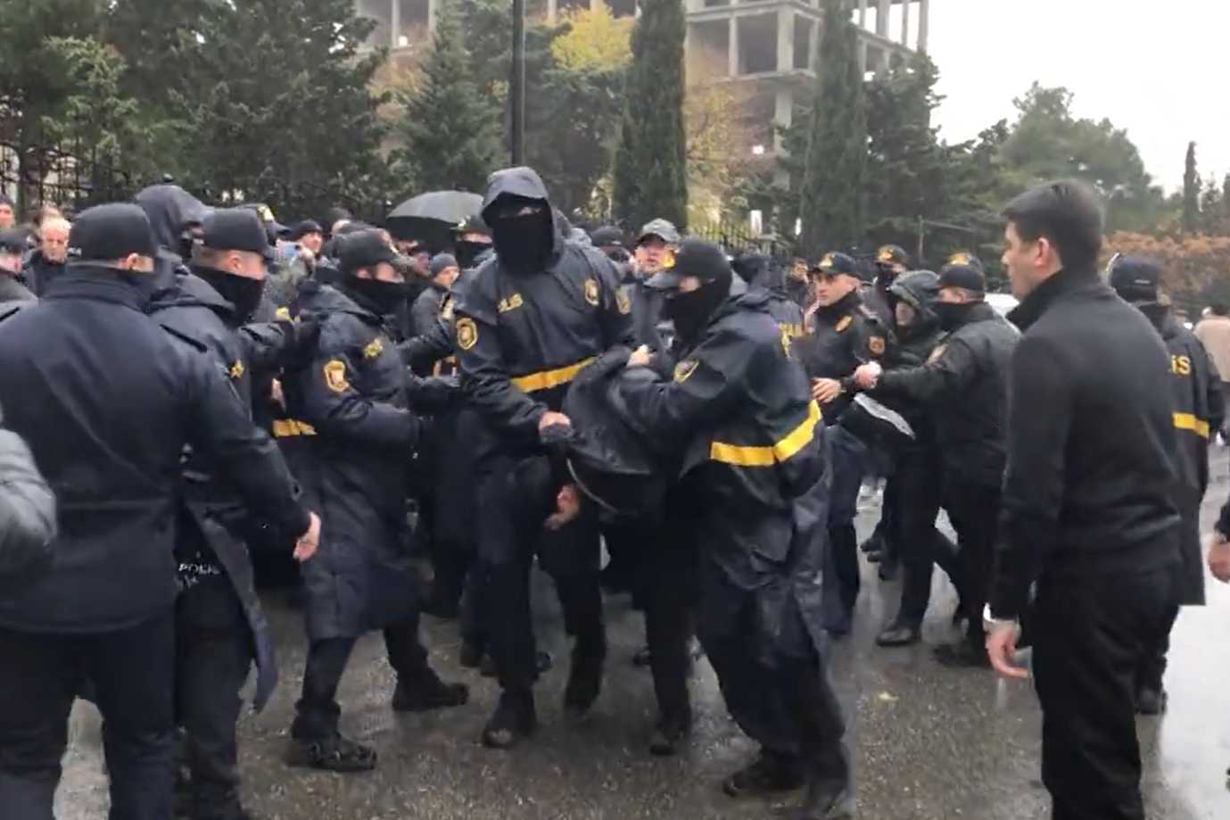 Police detaining an unidentified individual outside the court where Popular Front Party chair Ali Karimli was being tried. Screengrab via RFE/RL.