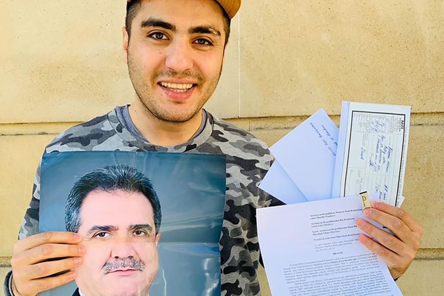 Blogger Mehman Huseynov holding a picture of MP Faraj Guliyev and the complaints he submitted against him to the authorities. Photo: Mehman Huseynov.