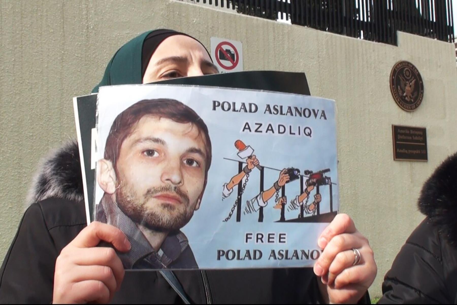 A protester holds up an image of Polad Aslanov. Photo via Voice of America.