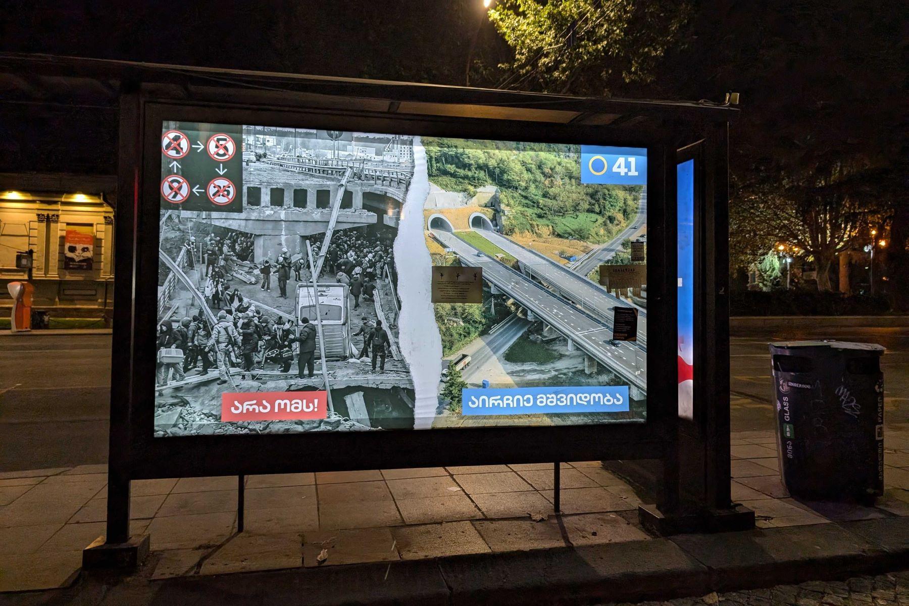 A Georgian Dream election banner on Rustaveli Avenue showing a destroyed bridge over the River Irpin in Ukraine and a highway in Georgia. Photo: Robin Fabbro/OC Media