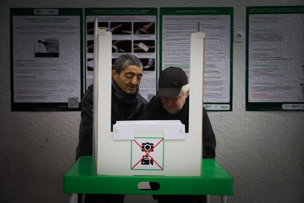 In the foreground, a man illegally ‘assists’ a voter in Tbilisi during the 2024 parliamentary elections. Photo: Hermine Virabian/OC Media