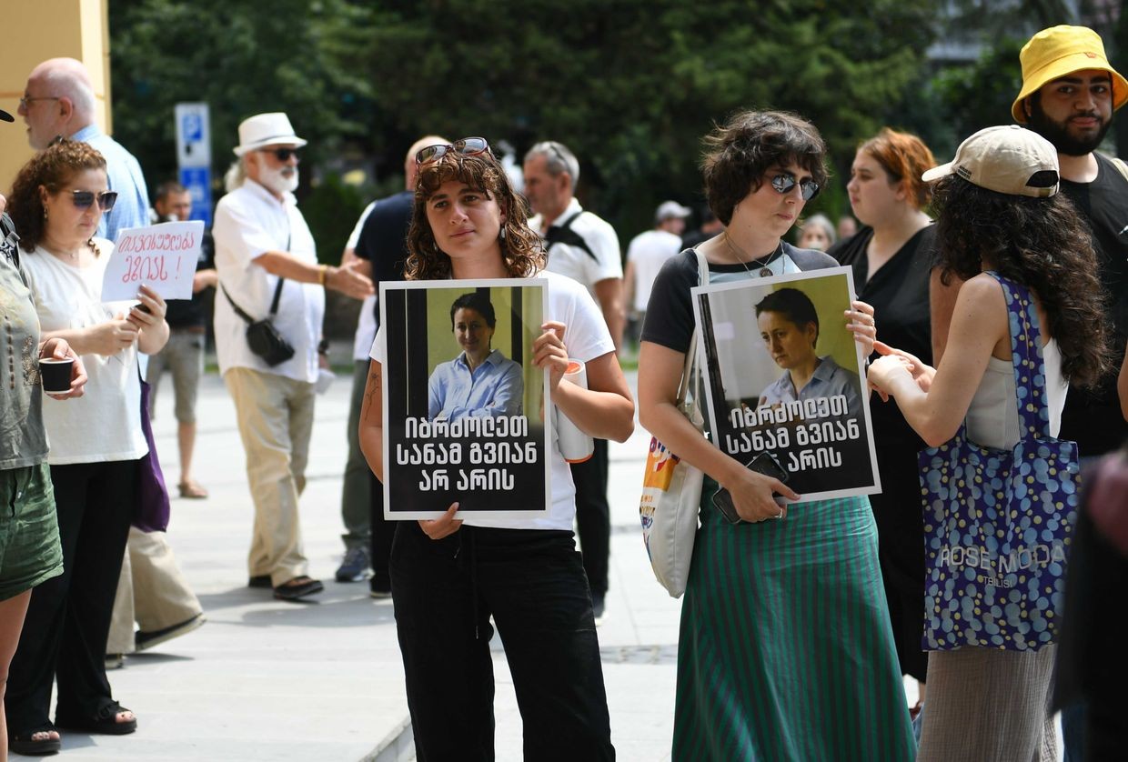 Activists at Batumi City Court holding photos of Mzia Amaghlobeli, featuring a quote from one of her statements from prison: ‘Fight before it’s too late’. Photo: Mariam Nikuradze/OC Media