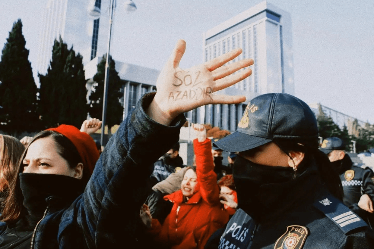 Ulviyya Ali protests against a media bill alongside other journalists, in front of the Azerbaijani Parliament in December 2021. The writing on her hand reads 'a word is free'. Photo via Ulviyya Ali/Human Rights Watch.