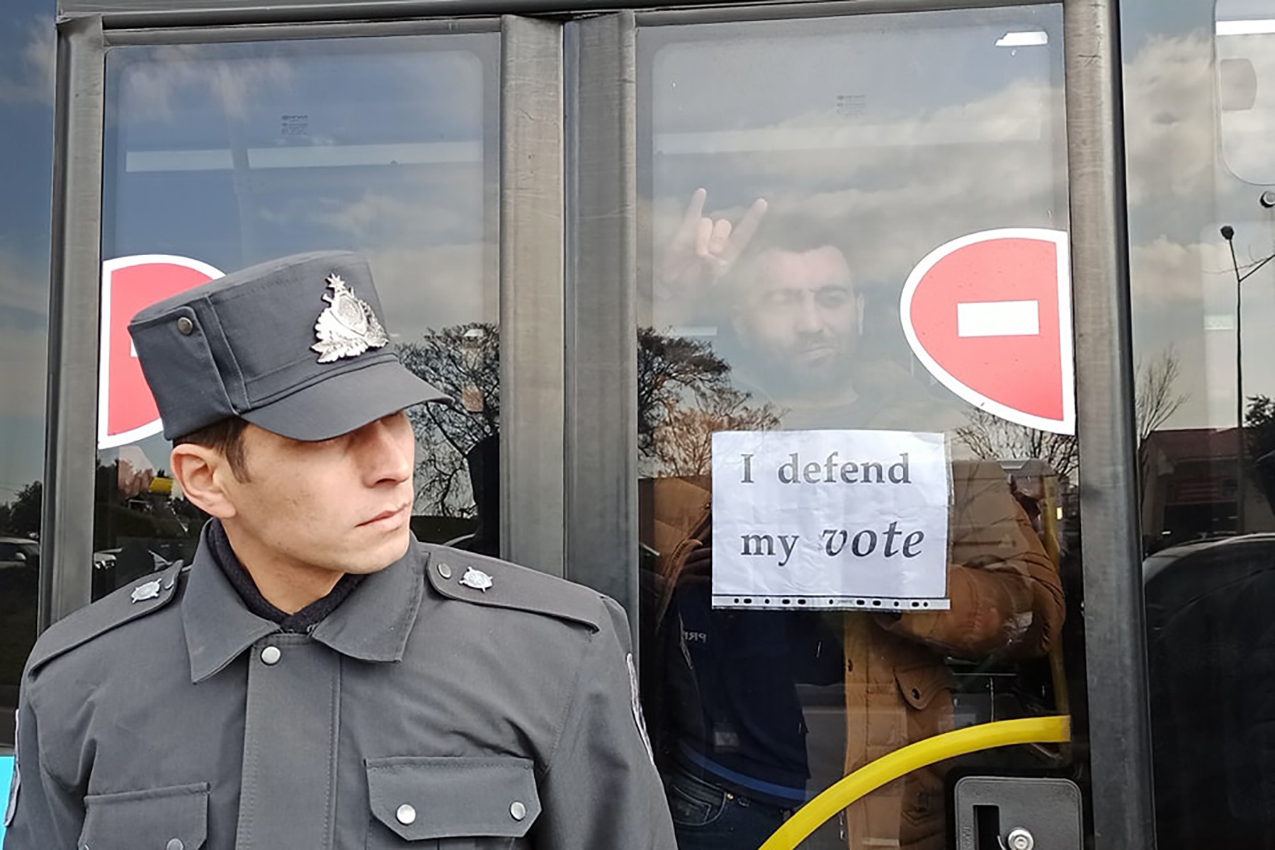 A police officer stands near a bus with protesters inside. Photo: Nurlan Gakhramanli