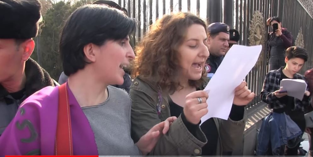 Protestors read the names of the victims of domestic violence.  Still from video. 
