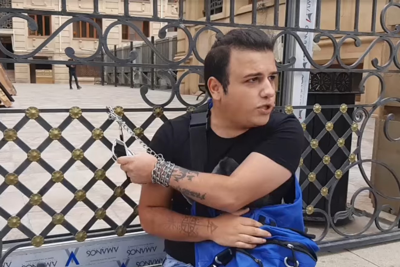 Avaz Hafizli chaining himself to the gates of the Prosecutor General’s Office in Septmeber 2021 to protest government inaction against homophobic incitement by popular Instagrammer Sevinj Huseynova. Image via Mikroskop.