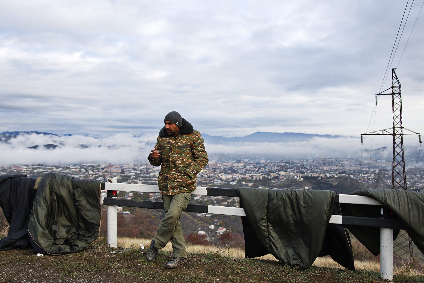An ethnic Armenian soldier smokes by drying sleeping bags on a motorway in Nagorno-Karabakh. Photo: Jack Losh.