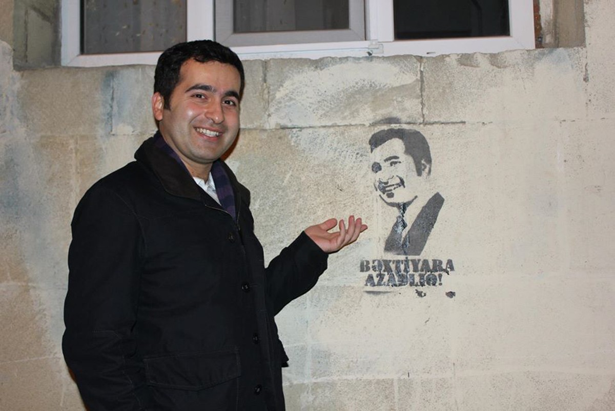 Bakhtiyar Hajiyev standing next graffiti calling for his release after he was arrested in 2012 for evading military service. Image via Facebook.