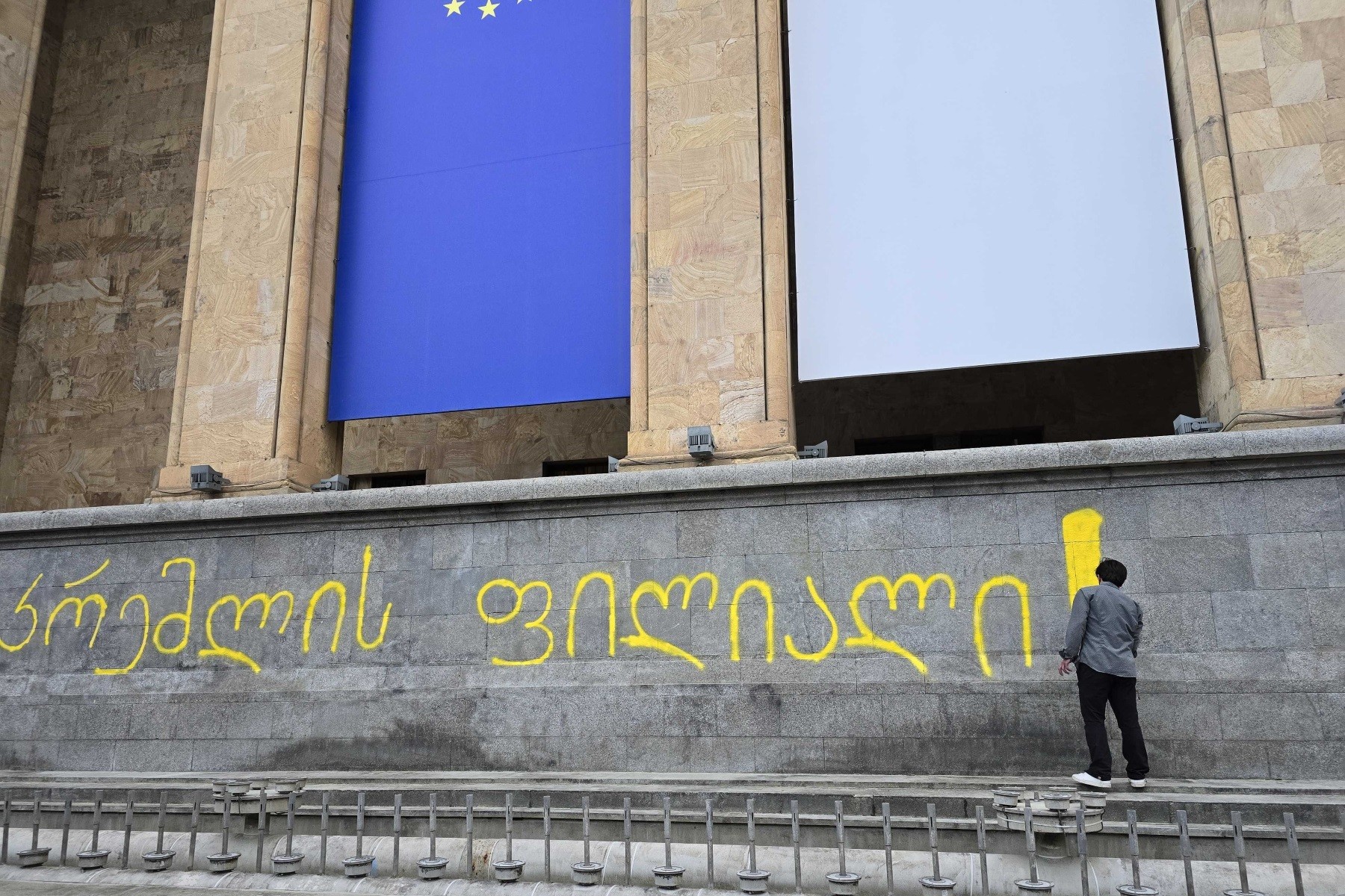 A person writes ‘Branch of the Kremlin’ on front of the Georgian Parliament 29 May 2024. Photo: Mariam Nikuradze/OC Media. 