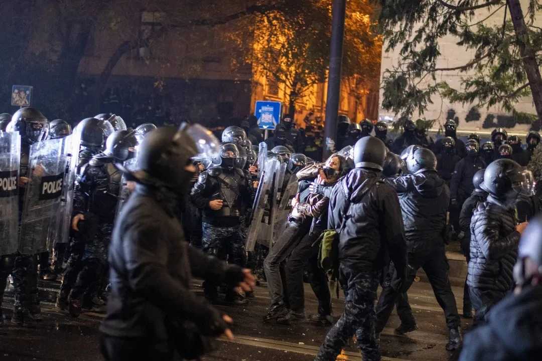 A protester is lifted up as the riot police advance during a dispersal on Rustaveli Avenuein winter 2024. Photo: Mariam Nikuradze/OC Media.