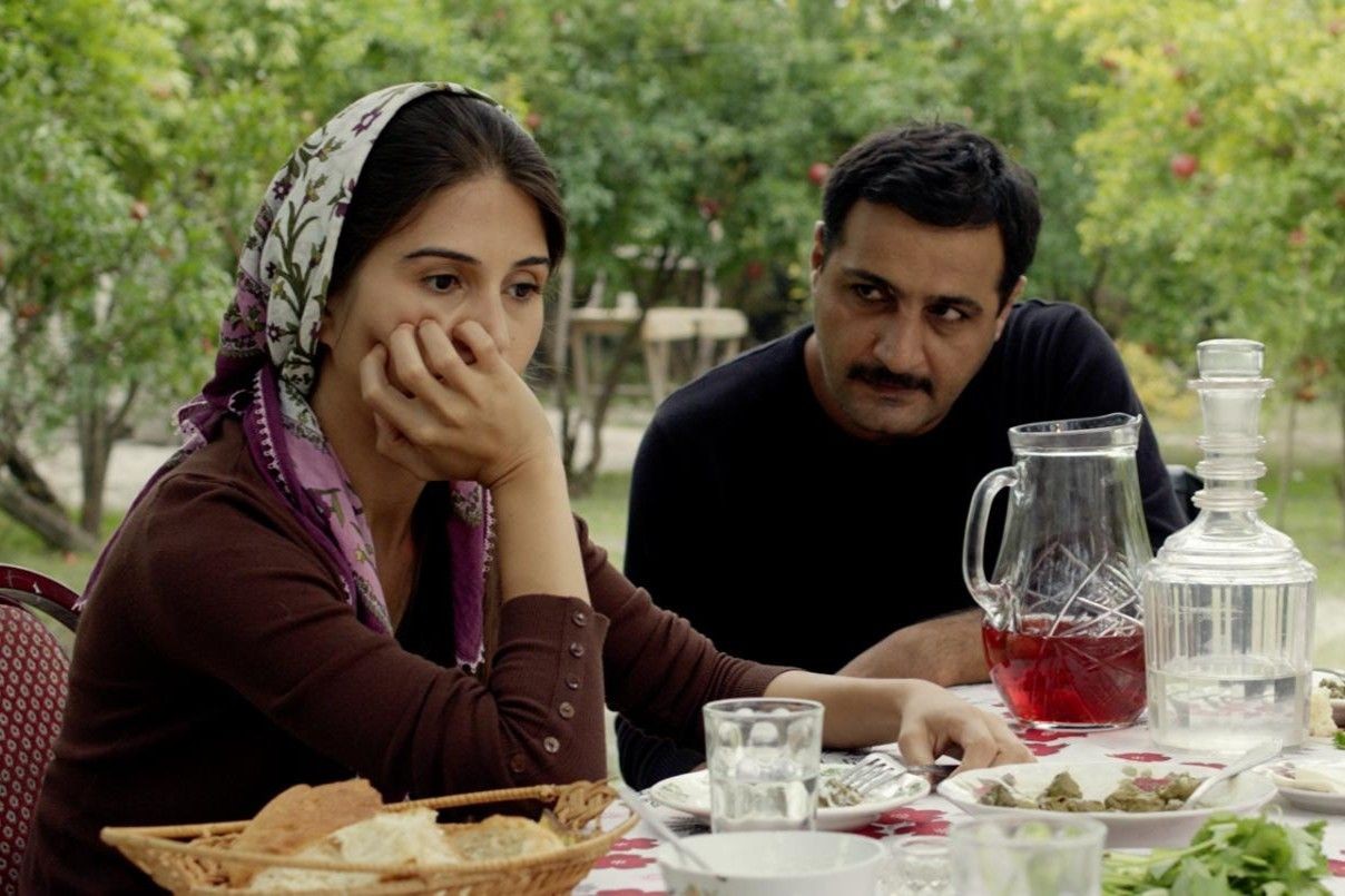 Sara (Ilaha Hasanov) and her husband Gabil (Samimi Farhad) sit in the Pomegranate orchard. Still from The Pomegranate Orchard.