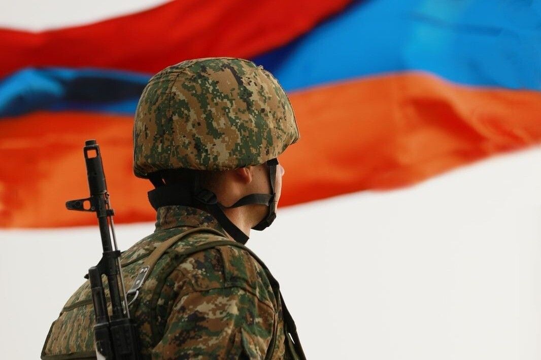 Armenian soldier with the Armenian flag in the background. Photo via Armenpress.