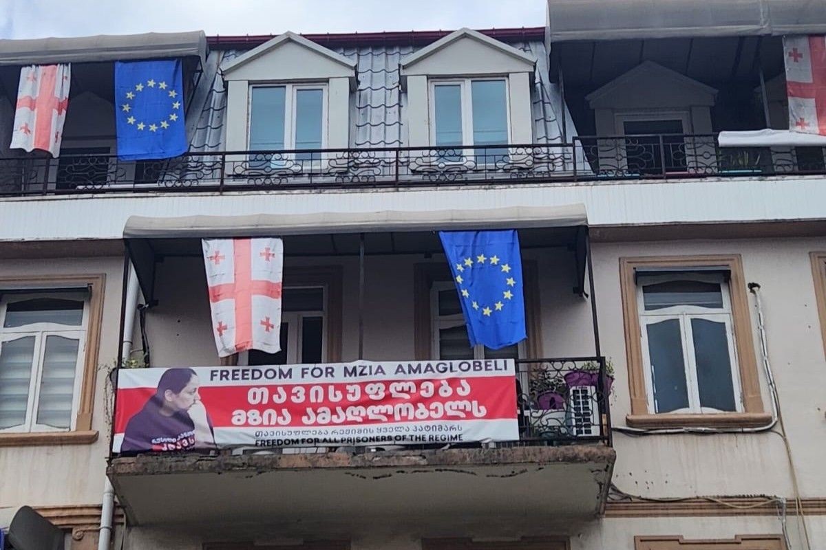 The facade of <em>Batumelebi’s </em>office in central Batumi displays a poster in support of Mzia Amaghlobeli, alongside the Georgian and EU flags. Photo: Givi Avaliani/OC Media.