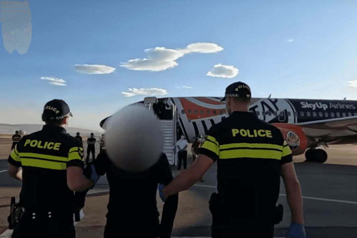 Police escort a Ukrainian who had been detained by the Russian border onto a plane bound for Ukraine. Screengrab from Georgian Interior Ministry video.