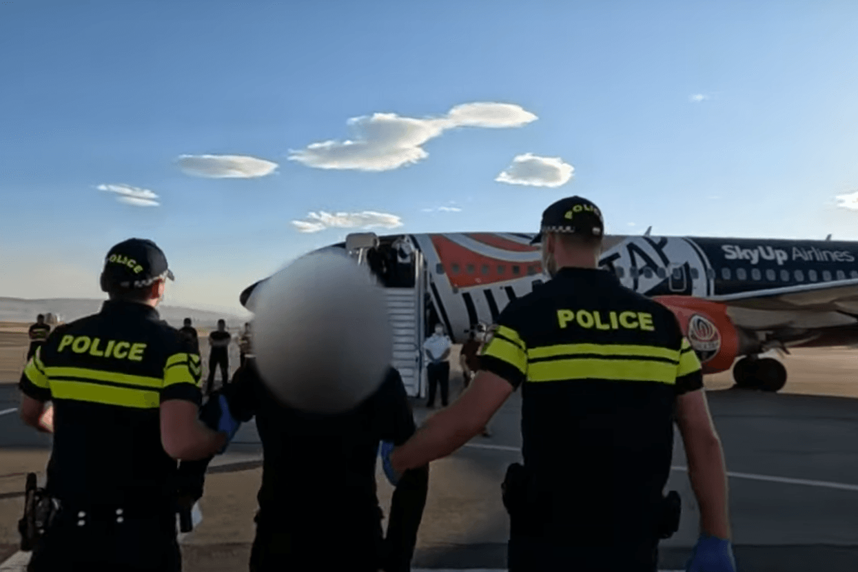 Police escort a Ukrainian who had been detained by the Russian border onto a plane bound for Ukraine. Screengrab from Georgian Interior Ministry video.