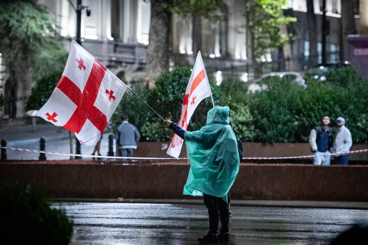 A demonstrator holding Georgian flags protests in front of parliament. Photo: Mariam Nikuradze/OC Media.