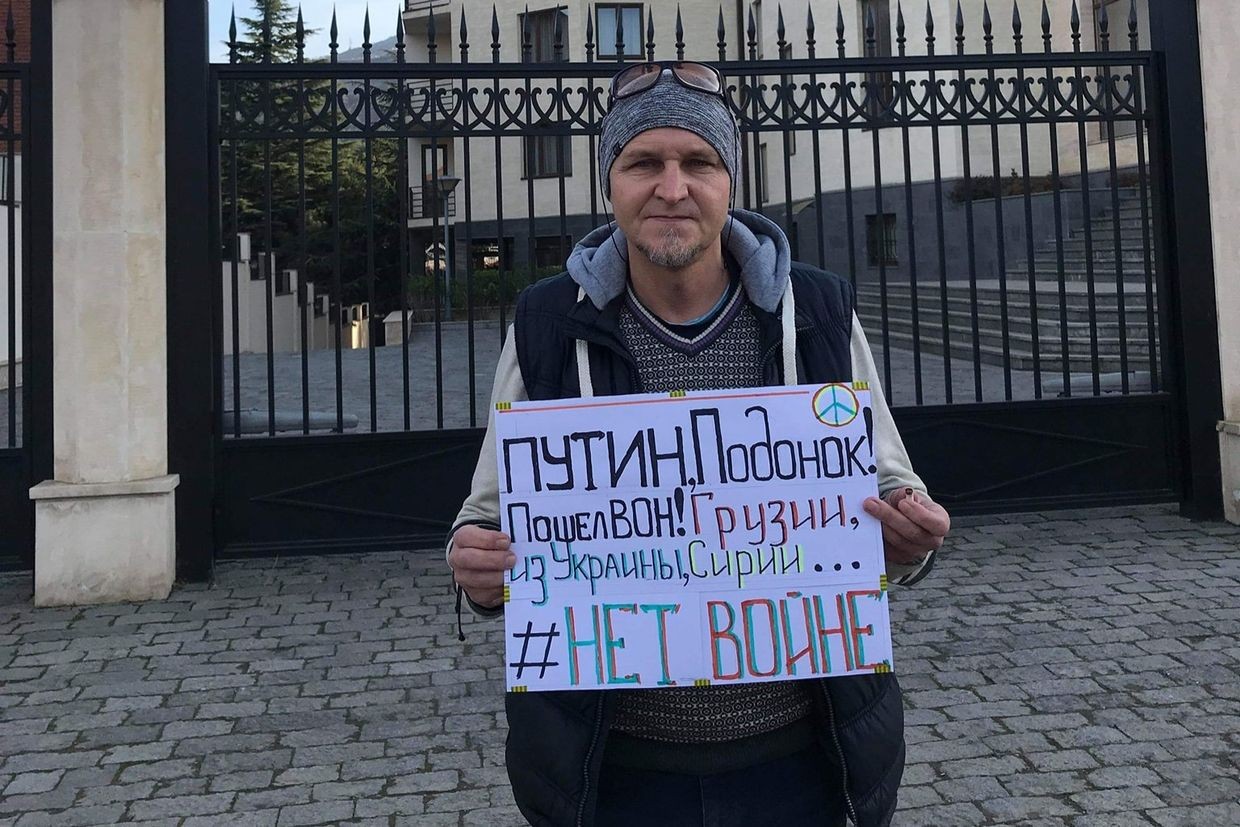 Nikolai Belikov standing outside the Ukrainian embassy in Tbilisi, holding a poster that reads: ‘Putin scumbag! Get out of Georgia, of Ukraine, of Syria… No war‘. Courtesay photo.