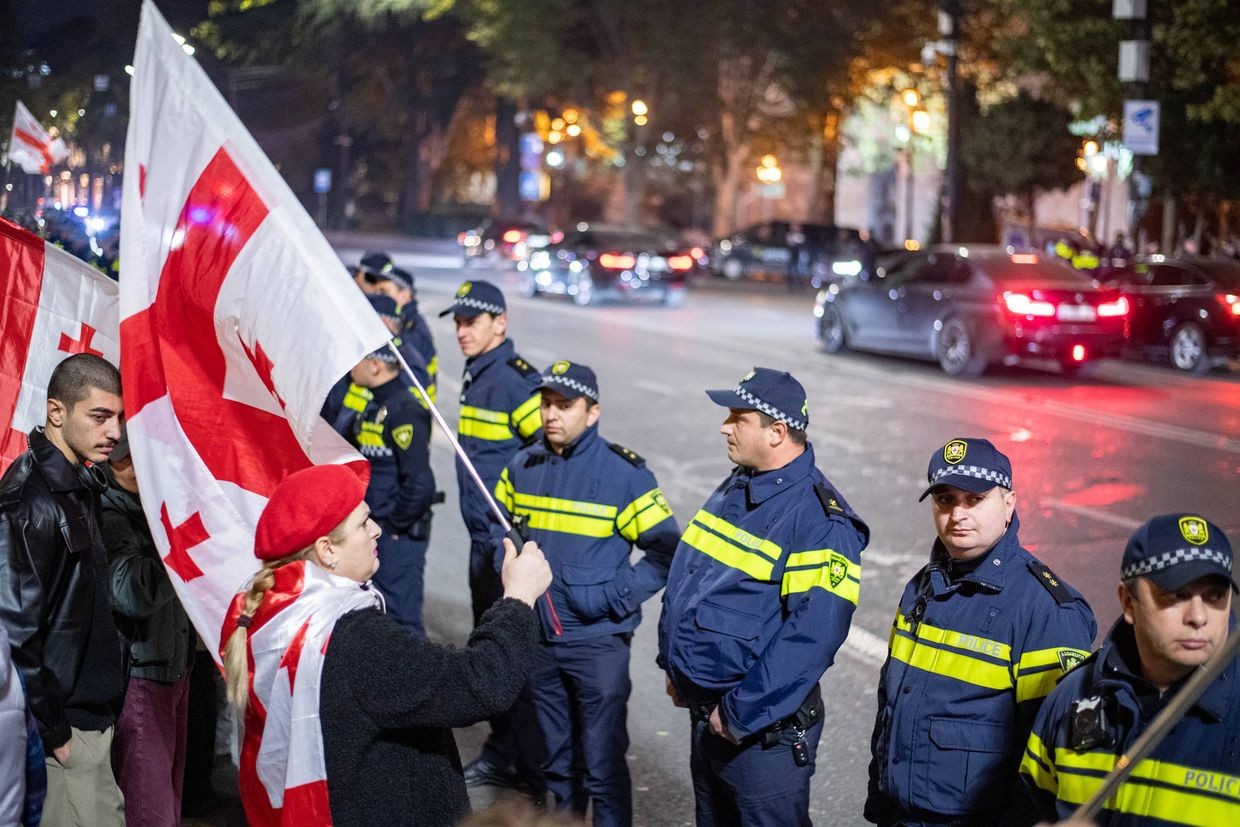 A protester with a Georgian flag faces police outside parliament. Photo: Mariam Nikuradze/OC Media.