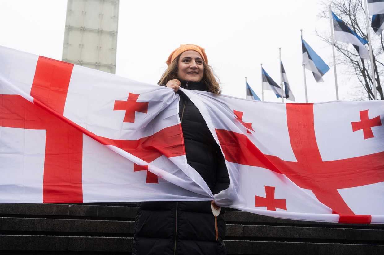 A woman holds two Georgian flags during a demonstration in Estonia. Photo via social media.