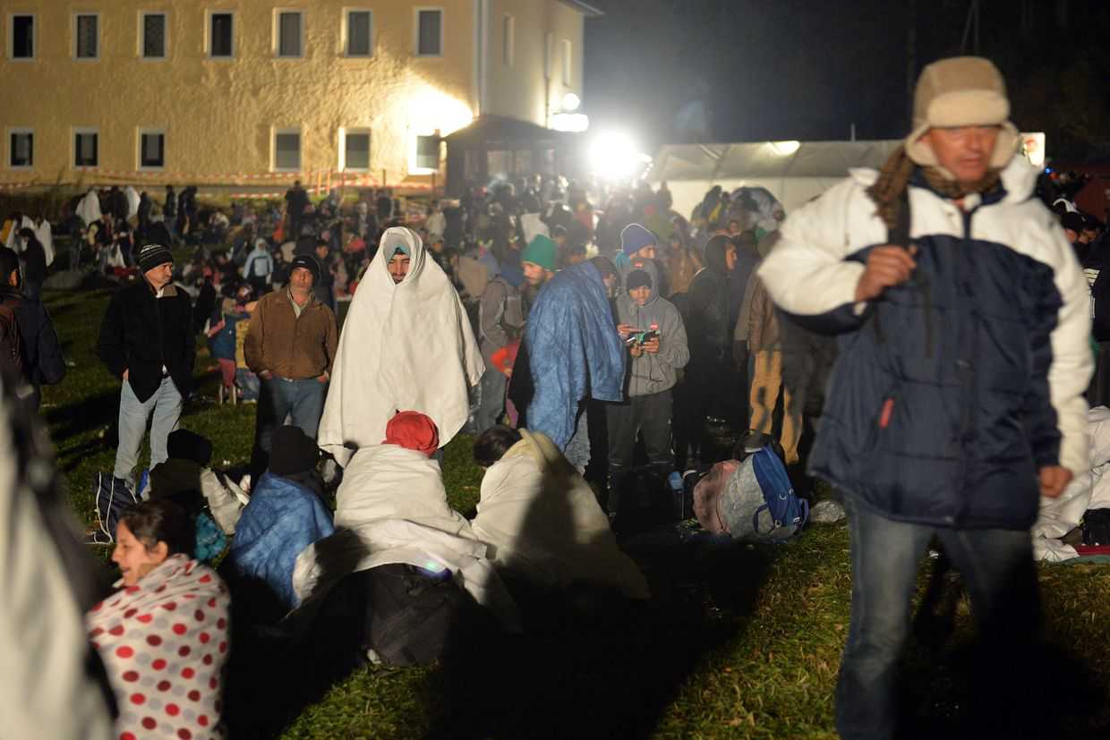 Migrants wait on a meadow at the border between Austria and Germany near Kollerschlag, Austria. Photo: AP/Kerstin Joensson.