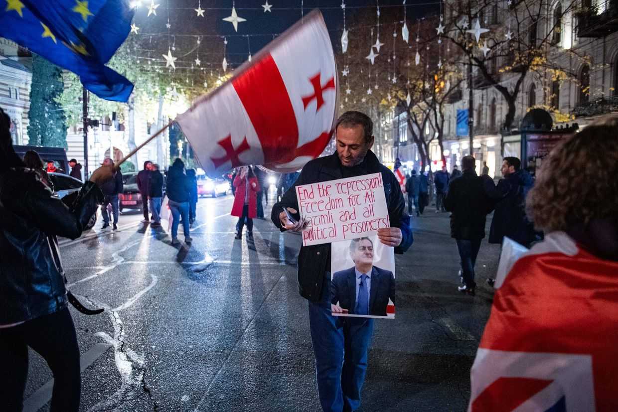 Afgan Sadigov at an anti-government protest in Tbilisi in December 2025, holding a banner calling for the release of Azerbaijani political prisoners. Photo: Mariam Nikuradze/OC Media. 