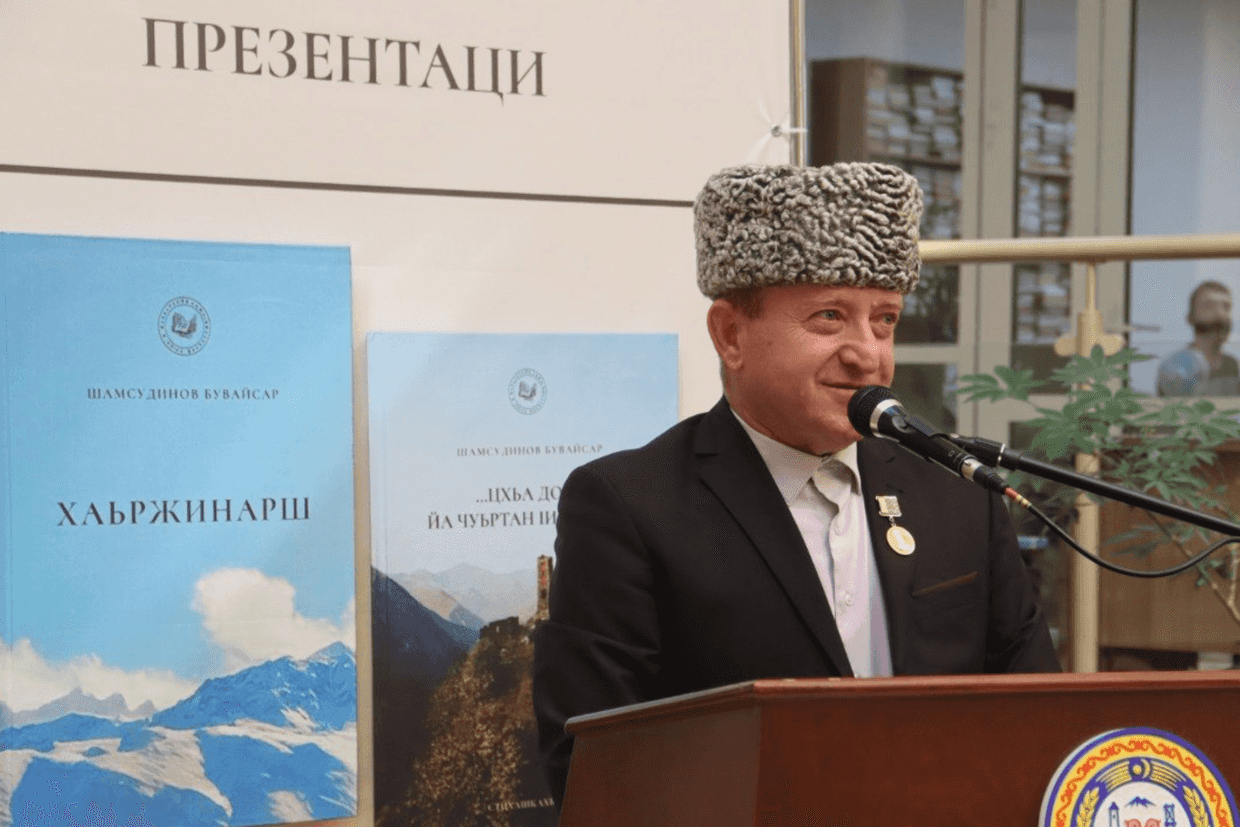 Buvaisar Shamsudinov and the banner with his books. Photo: Chechnyatoday.com