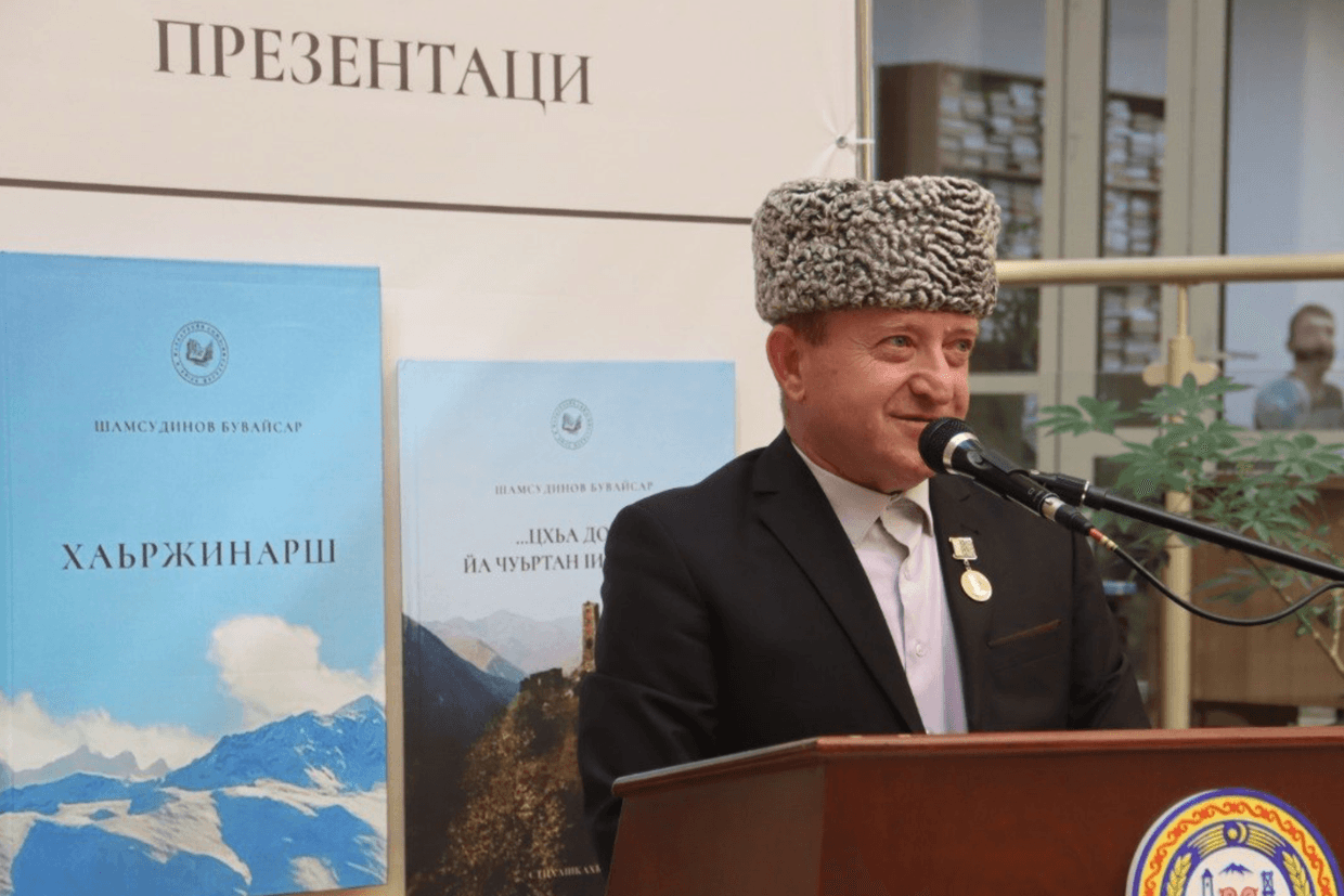 Buvaisar Shamsudinov and the banner with his books. Photo: Chechnyatoday.com