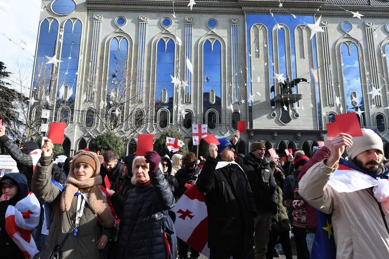 Protesters carry Georgian flags and red cards in protest of Mikheil Kavelashvili's inauguration as Georgia's sixth president earlier today. Photo: Mariam Nikuradze/OC Media.