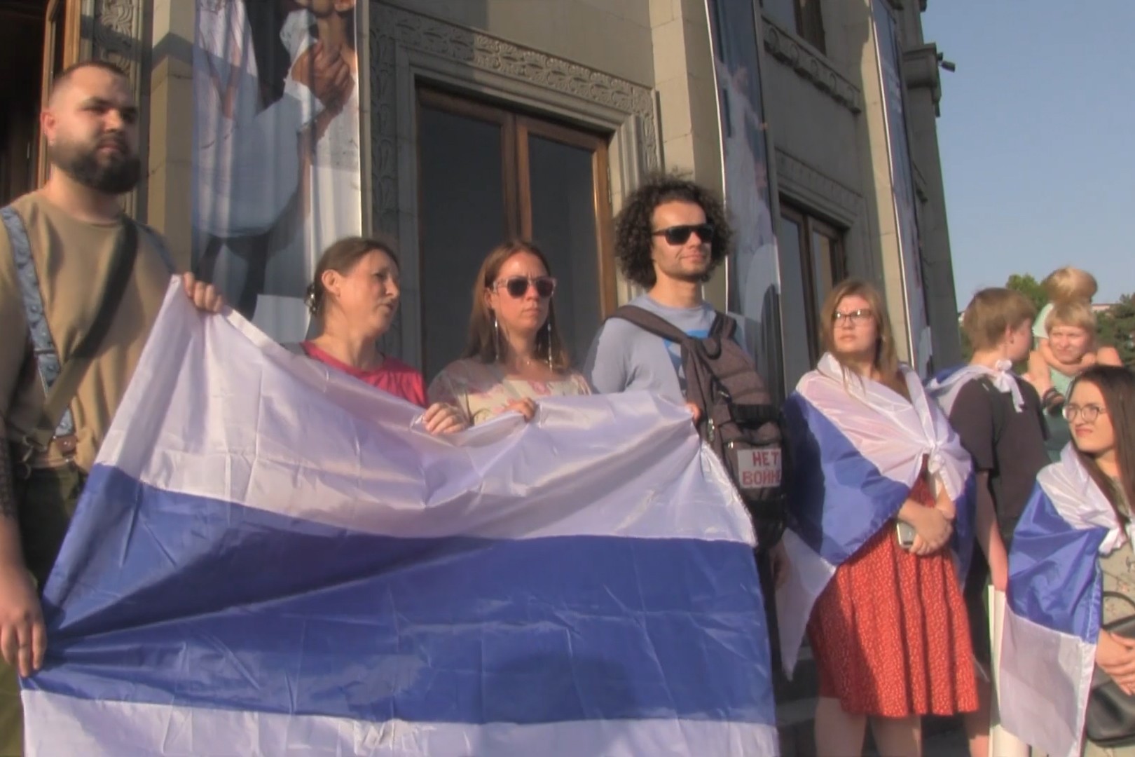 Protesters hold the white-blue-white flag of Russia, which has come to symbolise opposition to the war among Russians. Image via epress.am.