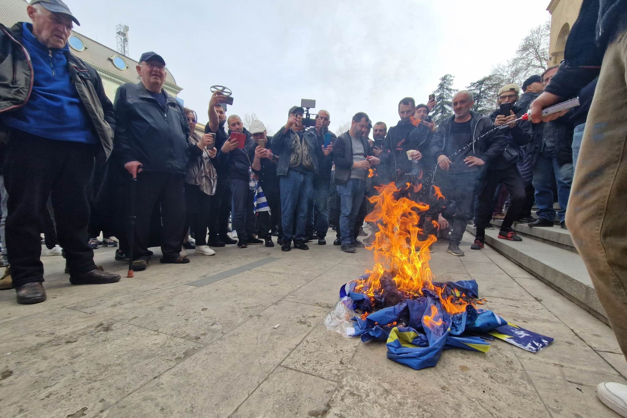 Members and supporters of Alt Info burn the flag of Europe after ripping it from the parliament. Photo: Mariam Nikuradze/OC Media.