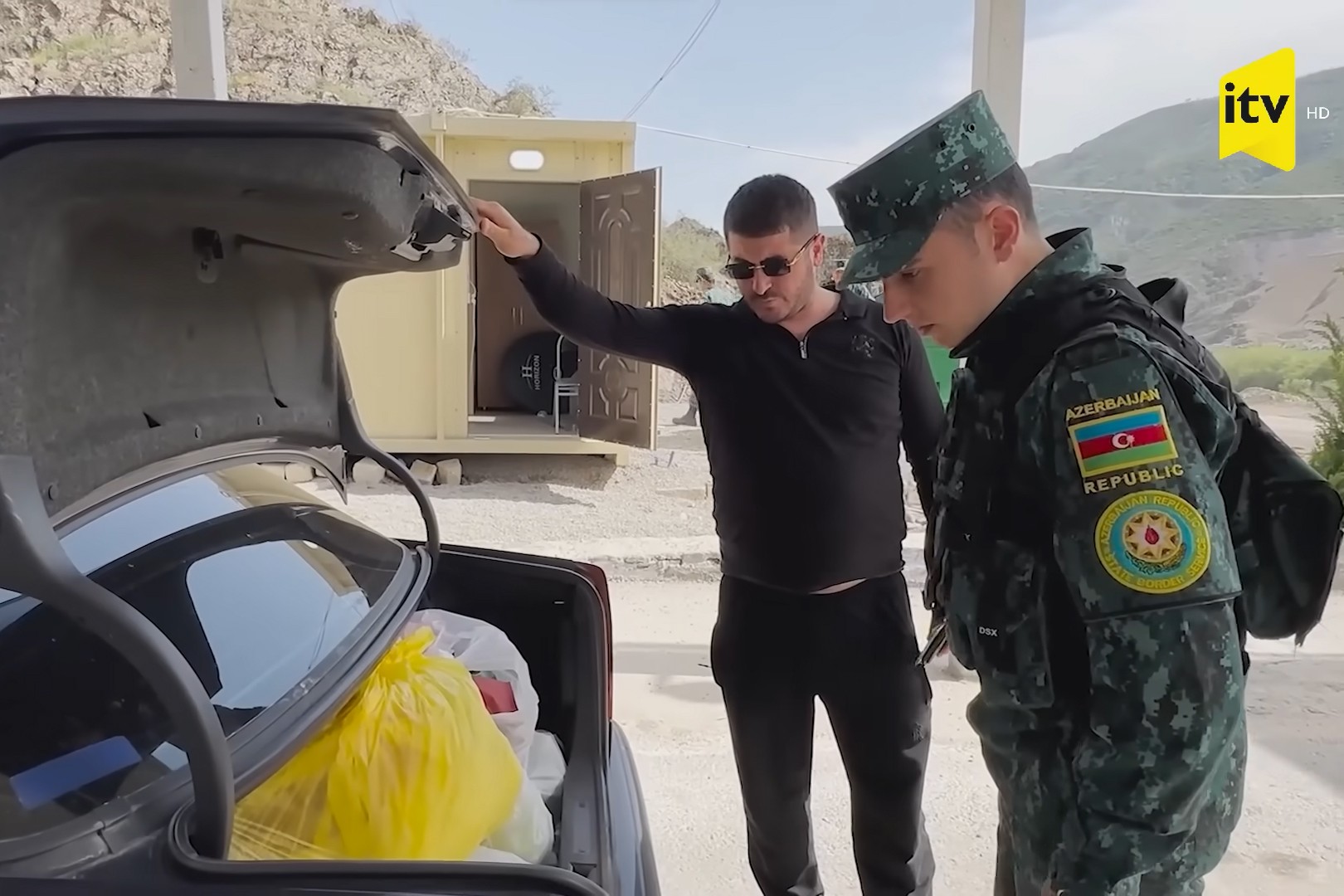 An Azerbaijani border guard inspects a vehicle at the checkpoint on the Hakiri Bridge. Image via ITV.