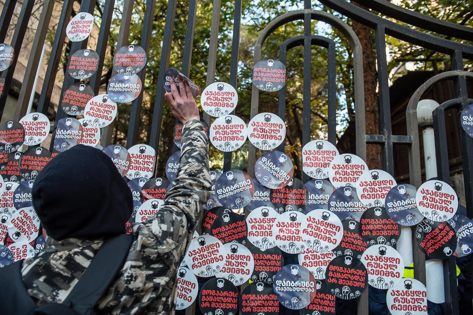 A Georgian protester placing stickers on the gate of the Tbilisi Court of Appeals. Mariam Nikuradze/OC Media.