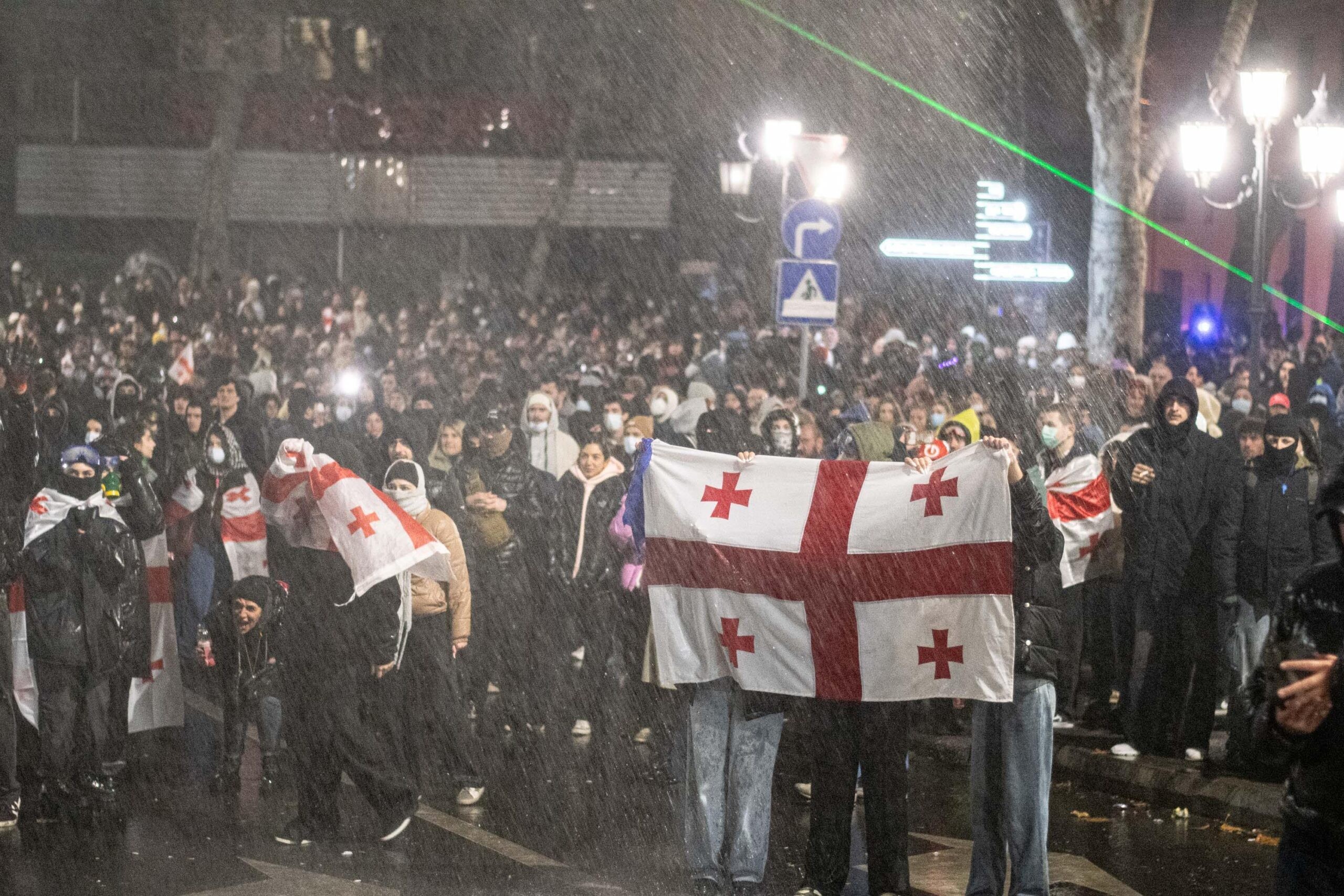 Protesters hold Georgian flags as riot police spray water at them. Mariam Nikuradze/OC Media.