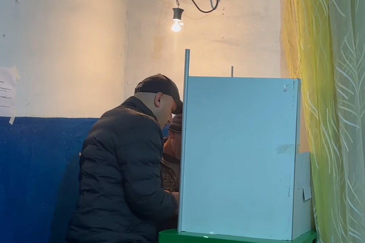 A State Security Service official identified by OC Media as Giorgi Mgeladze, brought in a person with a disability to vote. He did not have an ID on him. Photo: Kristina Kvatchantiradze/OC Media