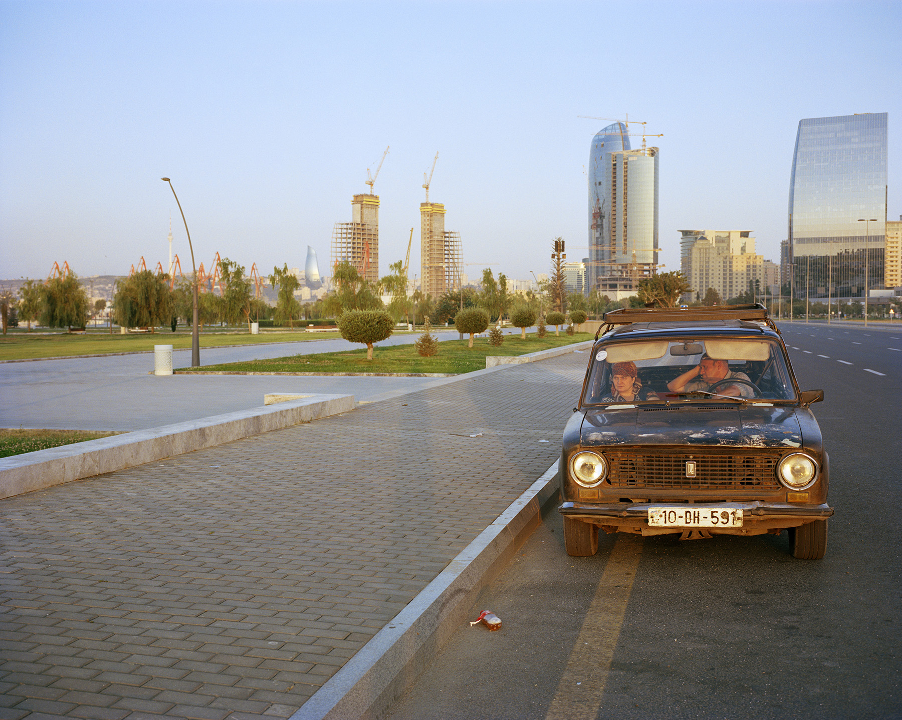 2016 год: Пара в старой «Ладе», а за ними порт Баку — зона роскошных магазинов; расположен в непосредственной близости от «Белого города» — элитного жилого комплекса. Цены на жилье в этом районе недоступны для большинства бакинцев.